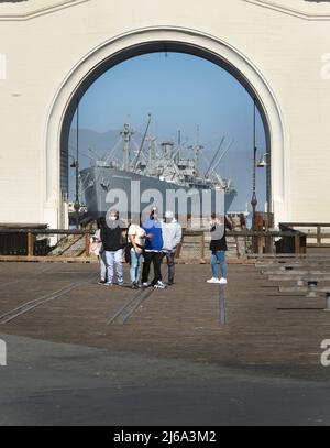 Tourists visit historic Pier 43 in San Francisco with the SS Jeremiah O'Brien World War II Liberty Ship, now based in San Francisco, in the distance. Stock Photo