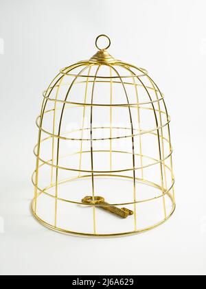 Big golden birdcage and vintage key on white background, concept, stock photo