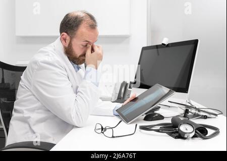 Young doctor rubbing his eyes, feeling tired and unhappy. Health care worker stress and frustration concept. High quality photography Stock Photo