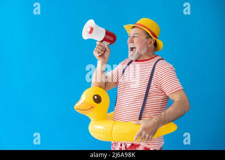 Happy senior man ready to travel. Funny man shouting through loudspeaker. Summer vacation and holiday concept Stock Photo