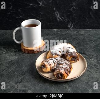 Cup of black tea and traditional chocolate pastries on a dark background, stock photo