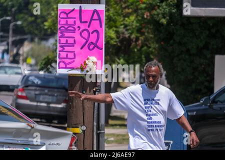 Los Angeles, USA. 29th Apr, 2022. April 29, 2022, Los Angeles, California, USA: A man walks by a sign reads â€œREMEMBER LA 92â€ at the intersection of Florence and Normandie after a press conference recognizing the 30th anniversary of the L.A. Riots at the corner of Florence Avenue and Normandie Avenue in Los Angeles, on Friday, April 29, 2022. (Credit Image: © Ringo Chiu/ZUMA Press Wire) Credit: ZUMA Press, Inc./Alamy Live News Stock Photo