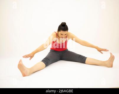 Athletic Woman In Tight Sportswear Practicing Yoga, Doing Head To Knee Pose  And Touching Toes While Exercising At Home On A Daytime Stock Photo,  Picture and Royalty Free Image. Image 164999271.