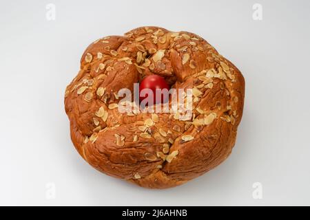 Tsoureki traditional baked Greek Easter sweet bread, garnished with slivered almonds and decorated with a boiled red dyed egg in the middle. Stock Photo