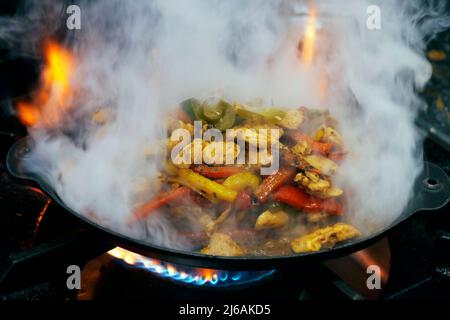 mexican food,fajitas with chicken, beef and peppers served on a hot smoking sizzling plate Stock Photo