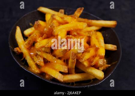 melted cheese potato fries ( potato chips ) in a serving bowl Stock Photo