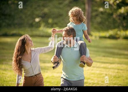 Foster care. Foster parents and son. Mother and child riding piggy back on father. Adoptive family Stock Photo