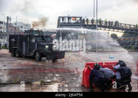 April 28, 2022, BogotÃ, Cundinamarca, Colombia: Protesters take cover from water cannons during the demonstration. Students clashed heavily with riot police at BogotÃ university as they marched to commemorate the day when the 2021 National Strike began in Colombia. (Credit Image: © Antonio Cascio/SOPA Images via ZUMA Press Wire) Stock Photo