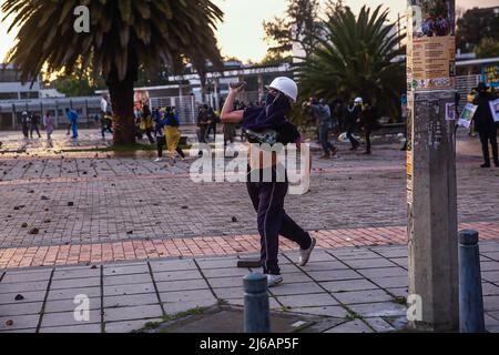 April 28, 2022, BogotÃ, Cundinamarca, Colombia: A female protester hurls stones at police officers during the demonstration. Students clashed heavily with riot police at BogotÃ university as they marched to commemorate the day when the 2021 National Strike began in Colombia. (Credit Image: © Antonio Cascio/SOPA Images via ZUMA Press Wire) Stock Photo