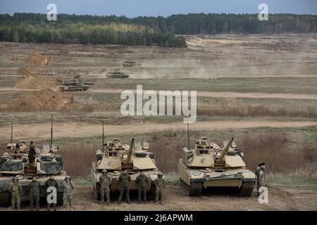 Polish and U.S. Soldiers from 2nd Battalion, 34th Armored Regiment, 1st Armored Brigade Combat Team, 1st Infantry Division stand at parade rest while waiting for a visit from the Polish Minister of Defense ahead of the Abrams Operations Summit at Bruchierz Range, Drawsko Pomorskie, Poland, April 25, 2022. The 1st Infantry Division is among other units assigned to V Corps, America's forward-deployed corps in Europe that works alongside NATO allies and regional security partners to provide command-and-control for rotational and set units in the European theater. (U.S. Army National Guard photo b