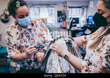 Woman dyes her hair in a barbershop, the process of dyeing her hair with foil. Stock Photo