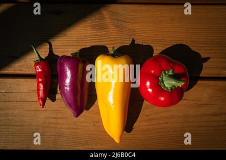 Group of colorful peppers on wooden background. Red, yellow, purple, and red hot chilly pepper Stock Photo