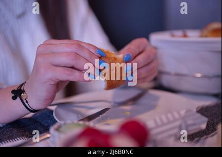 Closeup of female's hands with blue nails holding piece of bread Stock Photo