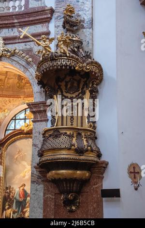 Baroque pulpit in the Karlskirche, Vienna. The abat-voix forms a canopy with two putti holding a cross and a chalice with host; flaming urn on the top Stock Photo