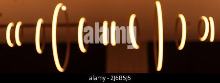 blurred hanging lamp bulb in the form of rings. blur beautiful abstract lighting under the ceiling from modern pendant electricity round lamps chandel Stock Photo
