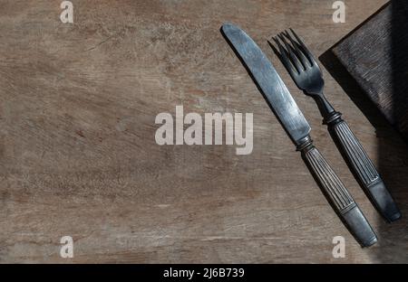 Vintage old metal knife with fork on old rustic wooden background. Eating concept, Copy space, Selective Focus. Stock Photo