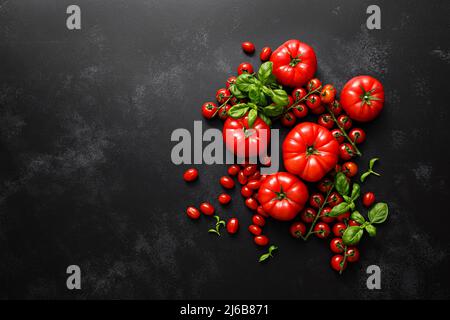 Tomatoes and basil on black background, top view, flat lay Stock Photo