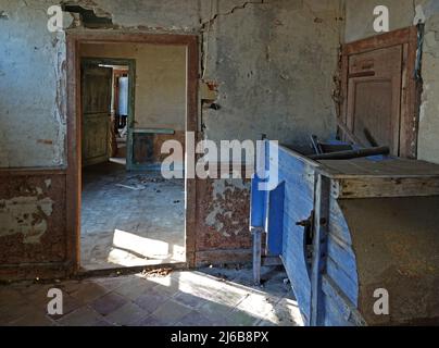 Old dilapidated spaces. The sunlight shines in through the window. You can see the following rooms through the doors. Holes in the wall. A lost place Stock Photo