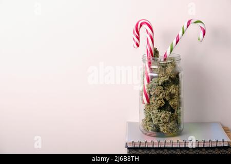 Drying hemp flowers. Cannabis buds and Christmas lollipops on white background. Marijuana blooms in a jar. Micro dosing concept. Stock Photo