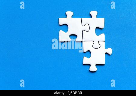 White pieces of a jig saw puzzle isolated on a blue background Stock Photo