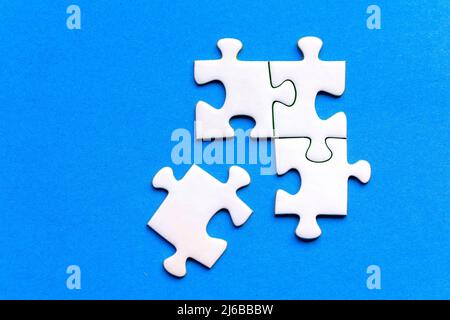 White pieces of a jig saw puzzle isolated on a blue background Stock Photo