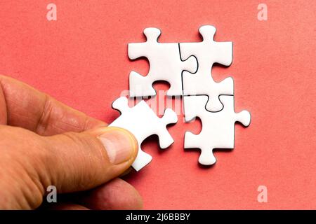 a human hand laying a piece of a jig saw puzzle Stock Photo