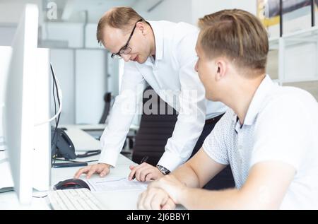 Employees of the company interact in the process of work and help each other in solving problems by discussing current goals. People in the office and Stock Photo