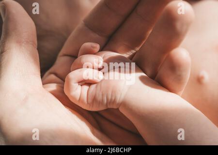 Baby's hand. The father holds with tenderness and love the small hand of the newborn. New life, parental protection, care, love, child and baby health. High quality photo Stock Photo
