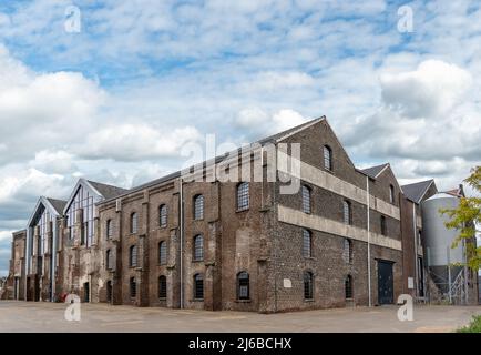Dark brick facade of an old abandoned factory. The stones are damaged and outdated, but new windows have been installed so that the restored building Stock Photo