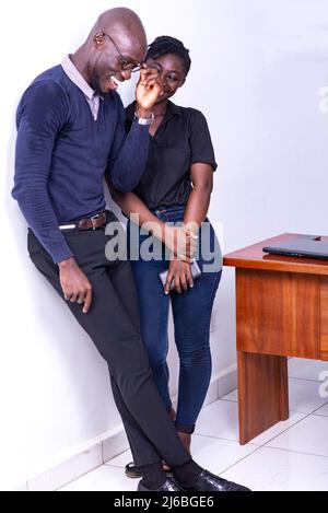 young colleagues standing in the office chatting laughing during break time Stock Photo