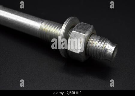Galvanized steel metal dowel with metric bolt and nut, isolated on black background Stock Photo
