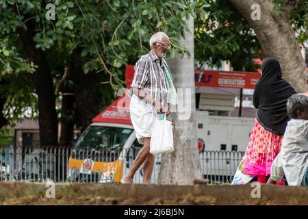 Vellore, Tamil Nadu, India - September 2018: An elderly Indian man walking holding a white plastic bag in his hand on the street. Stock Photo