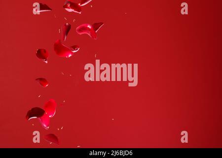 Red Rose Petals Falling in Front of Red Background Stock Photo