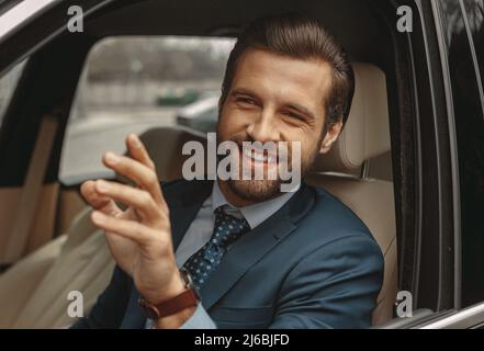 Bearded business man in formal clothes smiling at the photo camera in automobile Stock Photo
