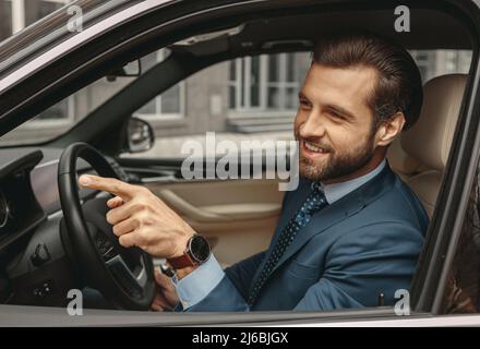 Adorable confident male in formal clothes gesturing in the automobile Stock Photo