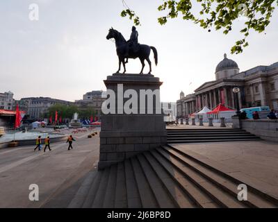 Three officials walk in Trafalgar Square after St Georges day celebrations have finished with the Equestrian statue centre. Stock Photo