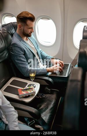 Bearded man using portable laptop in airplane Stock Photo