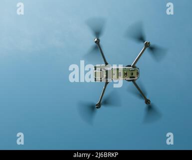 The image of the drone flying in the air taken from the ground at a deep angle. Stock Photo