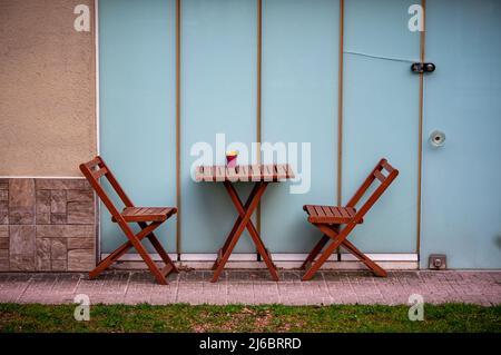 Wooden table and chairs standing in front of glass wall. Stock Photo