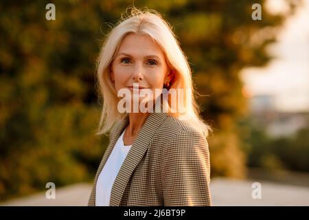 Mature white businesswoman wearing suit posing and looking at camera outdoors Stock Photo