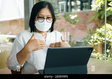 senior woman aged 60-69 years using tablet, watching lesson Sign language online course communicate by conference video call from home, e-learning edu Stock Photo