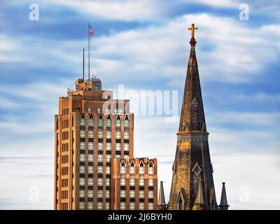 Sackets Harbor, New York, USA. April 23, 2022. The steeple of St. Paul’s Episcopal Cathedral and top floors of The State Tower Building in downtown Sy Stock Photo