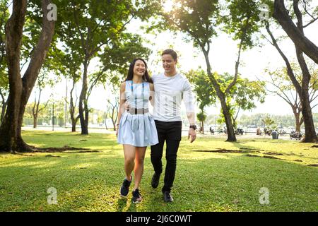 Smiling multiethnic lovers walking through a park Stock Photo