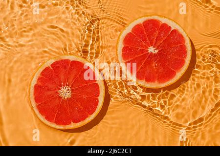 Texture summer citrus red raw fresh grapefruit with fresh water and waves. Summer minimal trend concept. Stock Photo