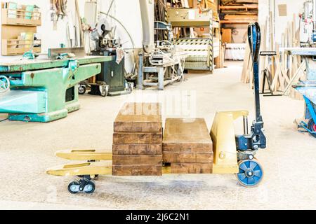 Pallet truck with wooden boards in light workshop Stock Photo