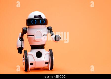Robot on an orange background with a place for text for a toy store and children's technology centers. Stock Photo