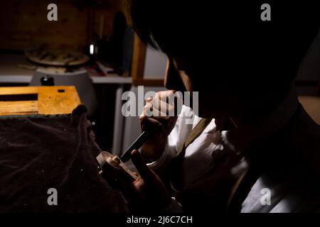 young Chinese female violin maker working with gouge to making a new violin in her workshop Stock Photo
