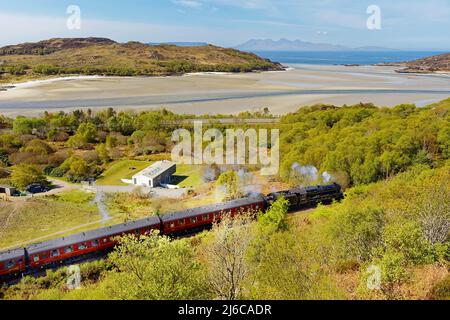 JACOBITE STEAM TRAIN NEAR MORAR STATION SCOTLAND TREES IN EARLY SPRING THE SILVER SANDS AND RUM ISLAND IN THE DISTANCE Stock Photo