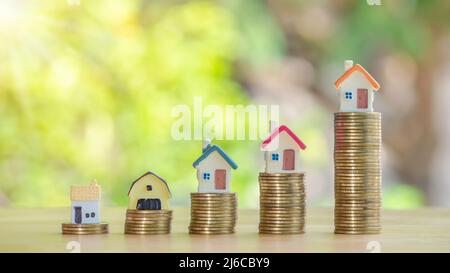 Home or house on gold coins 4 rows on wooden table..Concept for loan, property ladder, financial, mortgage, real estate investment, taxes, housing loa Stock Photo