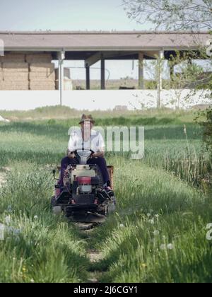 senior italian farmer transporting seeds in his small tractor in the fields Stock Photo